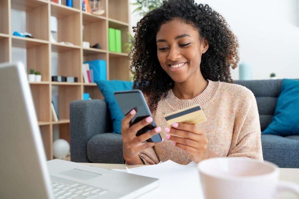 cheerful-young-black-woman-using-credit-card-at-home-1277139299-15ae3b7f10974d00bfe4a746c67f4742